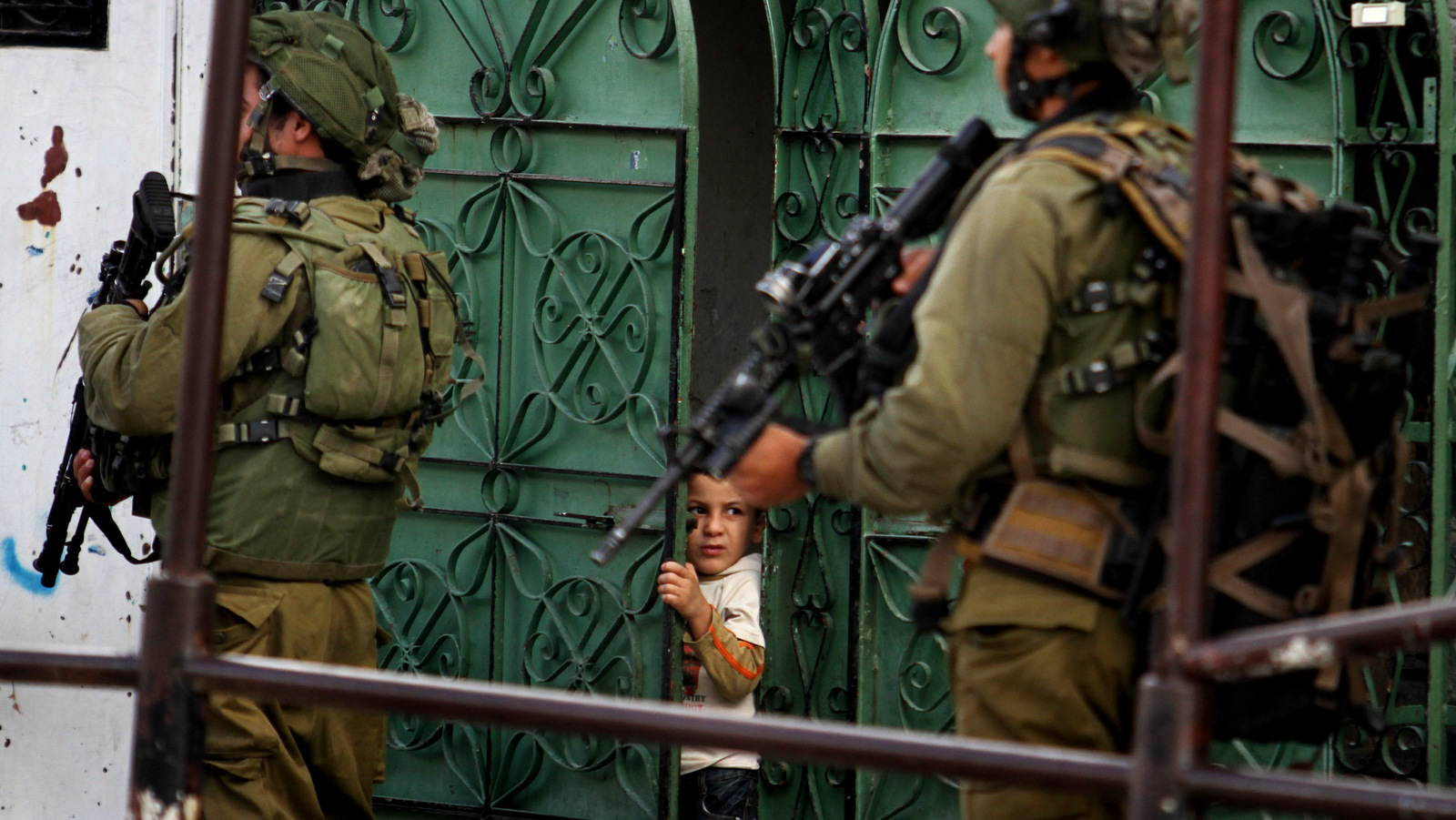 A Palestinian child looks at Israeli soldiers patrolling in the West Bank city of Hebron, Monday, Sept. 23, 2013. (AP/Nasser Shiyoukhi)