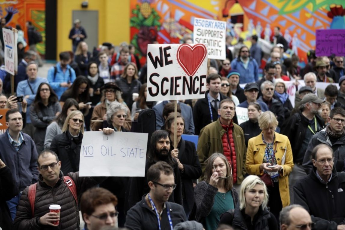 People hold signs as they listen to a group of scientists speak during a rally in conjunction with the American Geophysical Union's fall meeting in San Francisco. (AP Photo/Marcio Jose Sanchez)