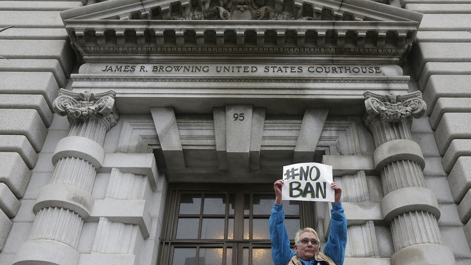 Karen Shore holds up a sign outside of the 9th U.S. Circuit Court of Appeals in San Francisco, Tuesday, Feb. 7, 2017. A panel of appeals court judges reviewing President Donald Trump's travel ban hammered away Tuesday at the federal government's arguments that the states cannot challenge the order. (AP/Jeff Chiu)
