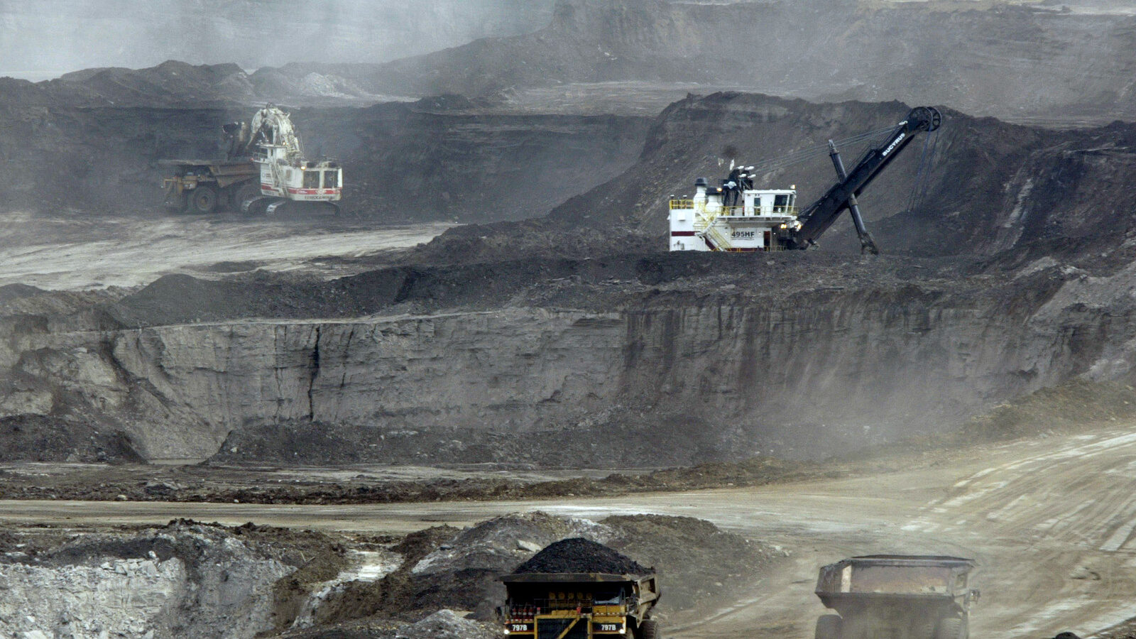 Mining trucks carry loads of oil laden sand after being loaded by huge shovels at the Albian Sands oils sands project in Ft. McMurray, Alberta, Canada. (AP/Jeff McIntosh)