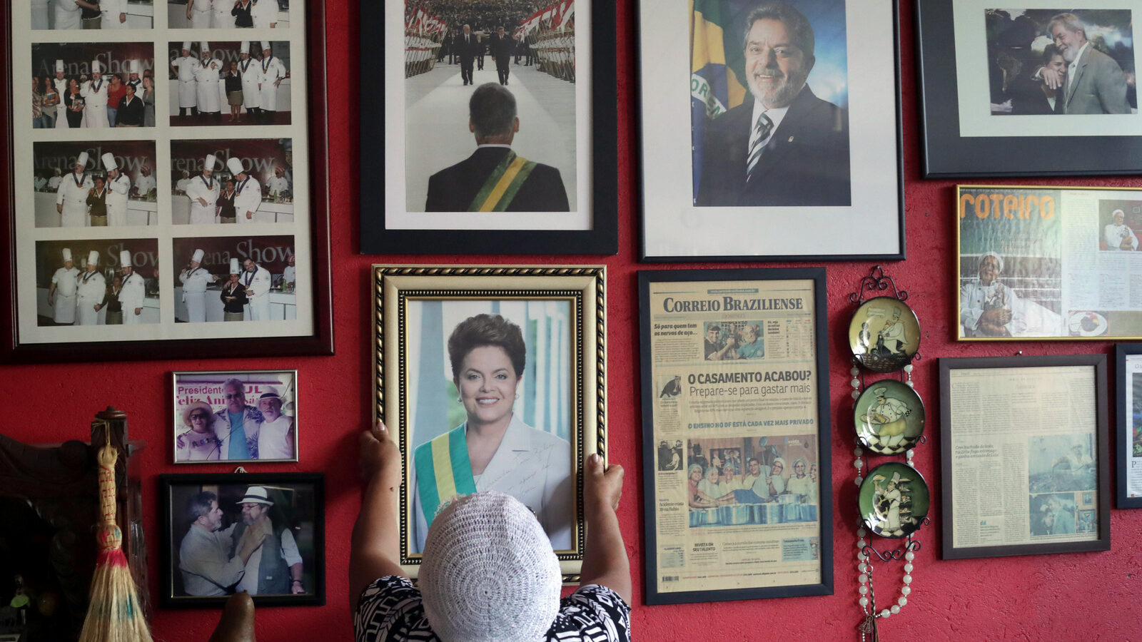 Maria de Jesus Oliveira da Costa, known as "Tia Zelia," takes down an autographed photo given to her by Brazil's impeached President Dilma Rousseff, to show it to journalists at her restaurant in Brasilia, Brazil, where photos of former President Luiz Inacio Lula da Silva also hang. (AP/Eraldo Peres)