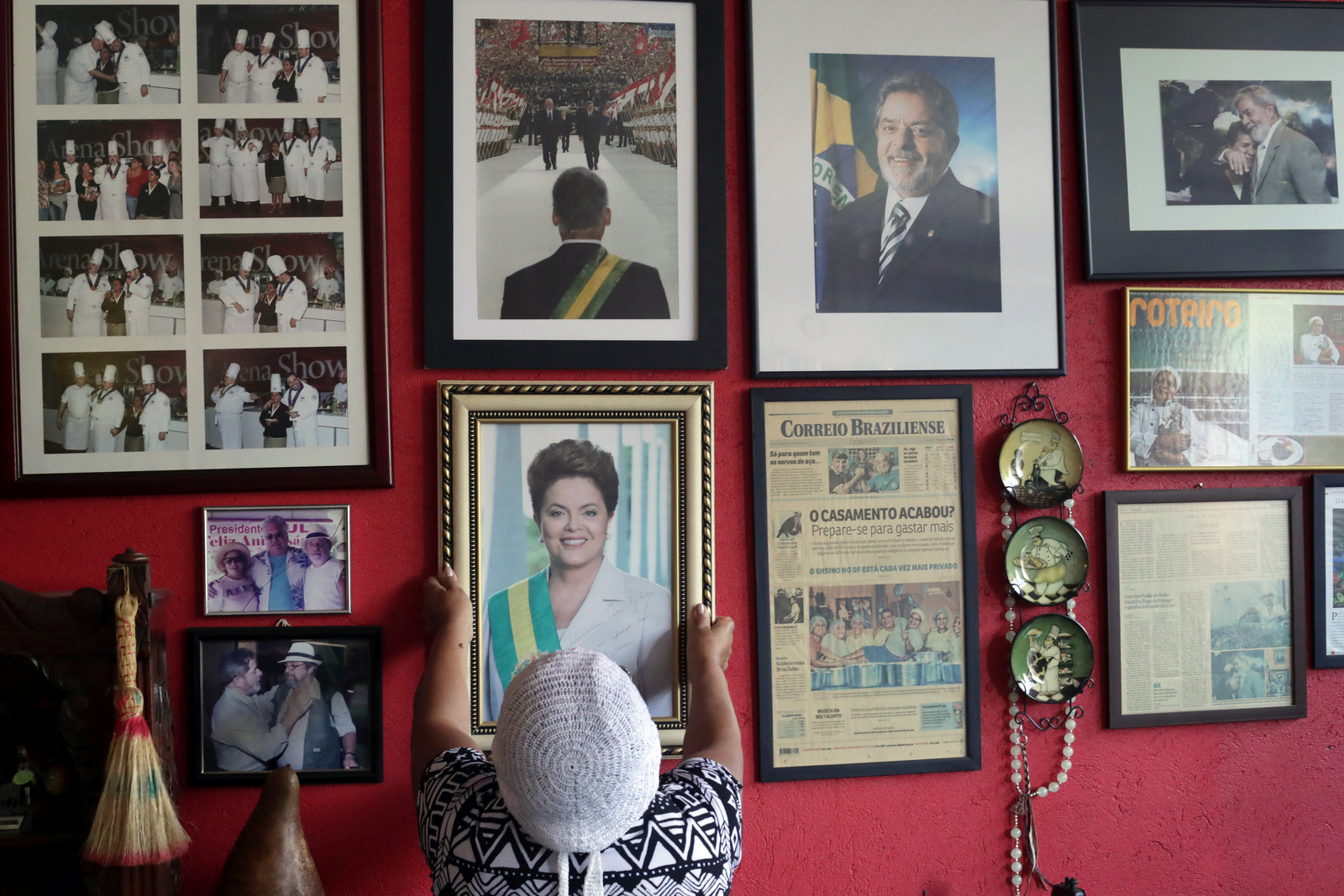 Maria de Jesus Oliveira da Costa, known as "Tia Zelia," takes down an autographed photo given to her by Brazil's impeached President Dilma Rousseff, to show it to journalists at her restaurant in Brasilia, Brazil, where photos of former President Luiz Inacio Lula da Silva also hang. (AP/Eraldo Peres)