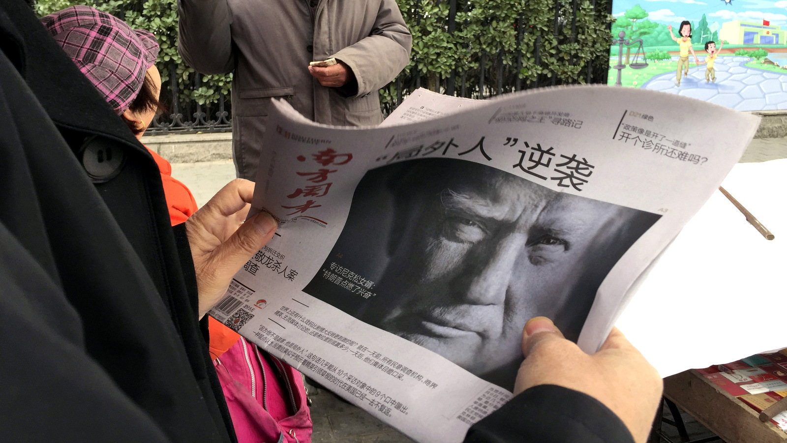 A Chinese man holds up a Chinese newspaper with the front page photo of Donald Trump and the headline "Outsider counter attack" at a newsstand in Beijing, China. (AP/Ng Han Guan)
