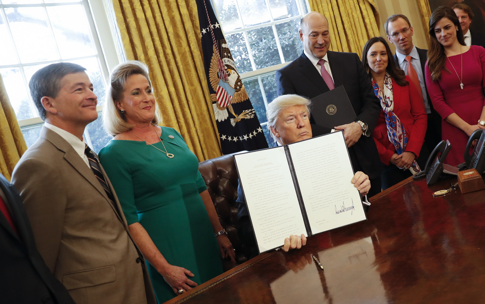 President Donald Trump holds up an executive order after his signing the order in the Oval Office of the White House in Washington, Friday, Feb. 3, 2017. The executive order that will direct the Treasury secretary to review the 2010 Dodd-Frank financial oversight law, which reshaped financial regulation after 2008-2009 crisis. On the far left are Rep. Jeb Hensarling, R-Texas, and Rep. Ann Wagner, R Mo. (AP/Pablo Martinez Monsivais)