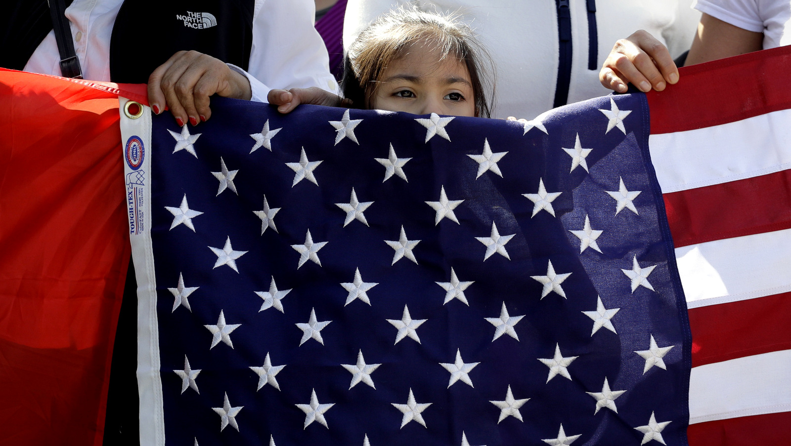 A young girl helps hold a U.S. flag as a group marches through downtown heading to the Texas Capitol during an immigration protest, Thursday, Feb. 16, 2017, in Austin, Texas. Immigrants around the U.S. stayed home from work and school Thursday to demonstrate how important they are to America’s economy and its way of life, and many businesses closed in solidarity, in a nationwide protest called A Day Without Immigrants. (AP/Eric Gay)