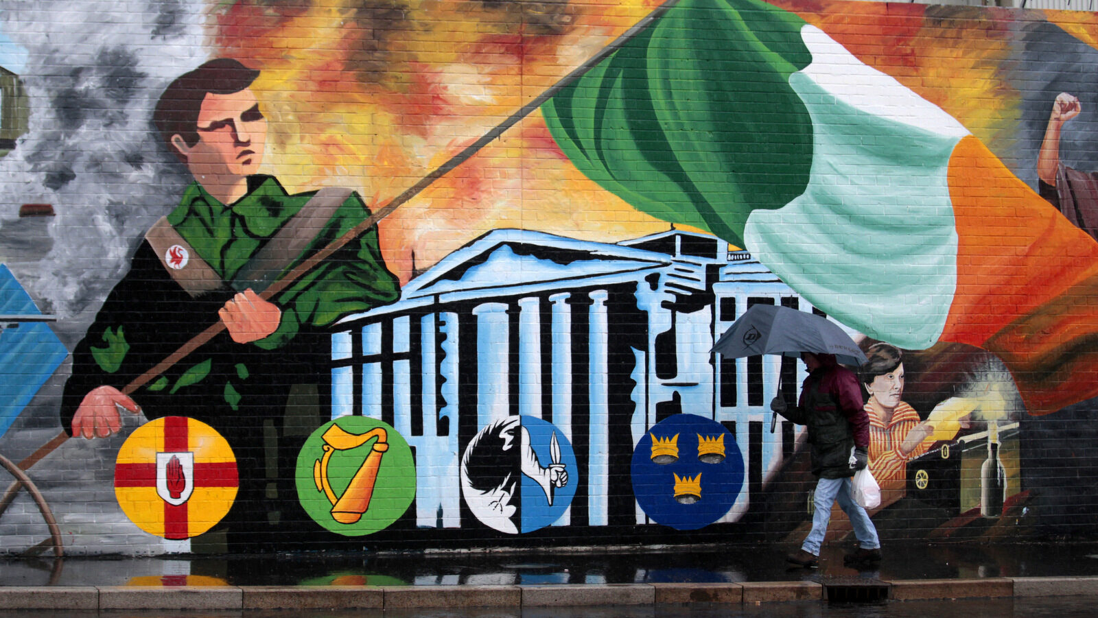 A man walks past a republican mural on the Falls road in West Belfast, Northern Ireland, Tuesday, Feb. 28, 2017. Voting is due to begin on Thursday in Northern Ireland after power sharing collapsed following the Renewable Heat Incentive scandal. (AP/Peter Morrison)