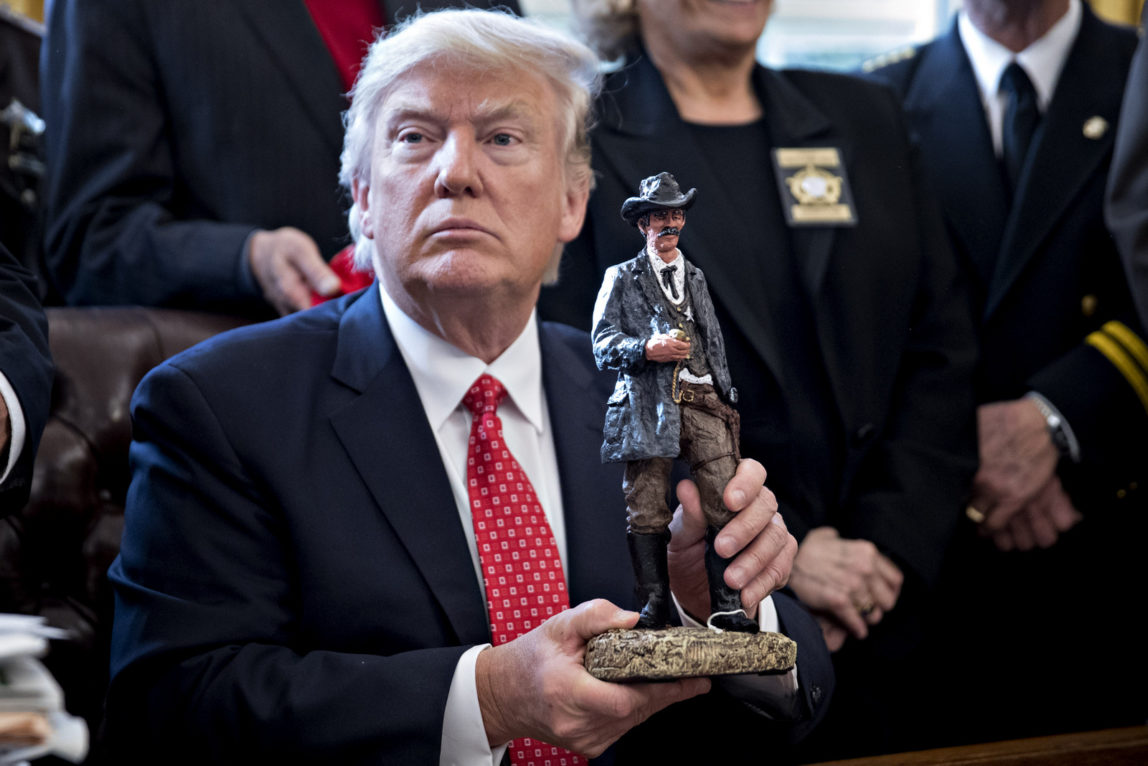 U.S. President Donald Trump holds up a statue he received as a gift while meeting with county sheriffs in the Oval Office of the White House in Washington, D.C., U.S., on Tuesday, Feb. 7, 2017. (Photo: Andrew Harrer/CNP/MediaPunch/IPX)