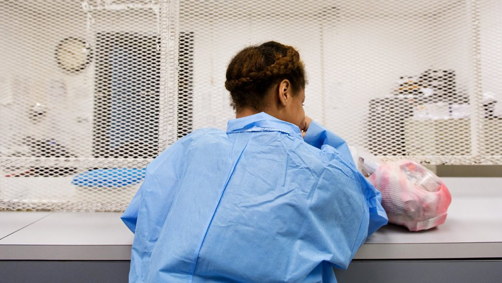 17-year-old Lena waits to be released from the Harris County Jail, with a small bag of her possessions. Her mentor gave her a blue jumpsuit to wear over her skimpy clothes. (Photo: Callie Richmond/The Texas Tribune)