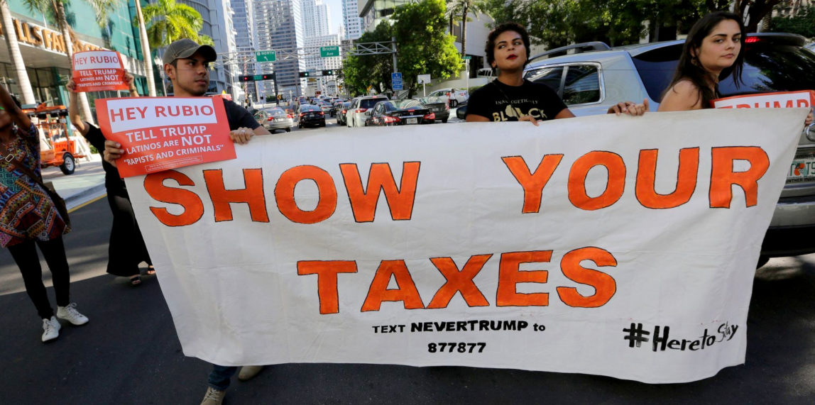 Marching protesters hold up a sign demanding that Republican presidential candidate Donald Trump release his tax returns, in Miami on Sept. 16. (AP/Lynne Sladky)