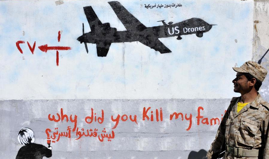 A Yemeni soldier looks at the graffiti of U.S. drone strike painted on a wall as a protest against the drone strikes, in Sanaa, Yemen, on Dec. 21, 2013. (Photo: Mohammed Mohammed/Xinhua)