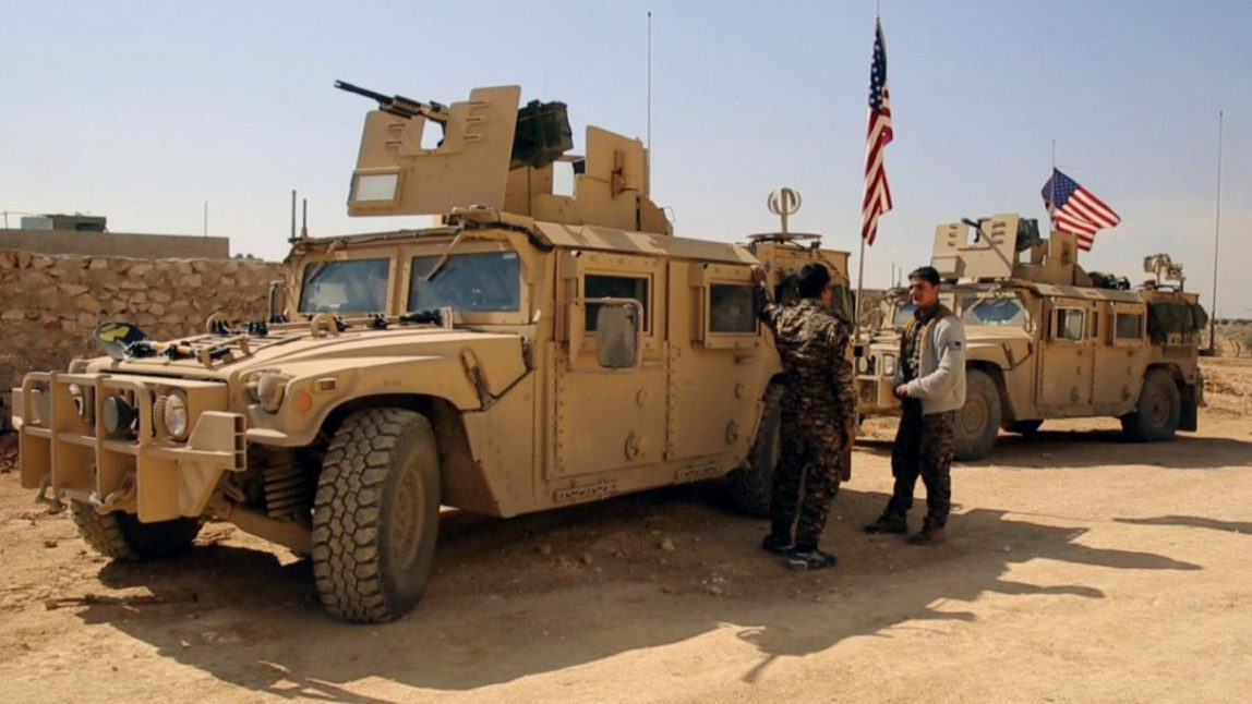 Syrian Rebel Fighters stand near U.S military vehicles on the outskirts of the Syrian town, Manbij, Syria, March 7, 2017. (Arab 24 via AP)