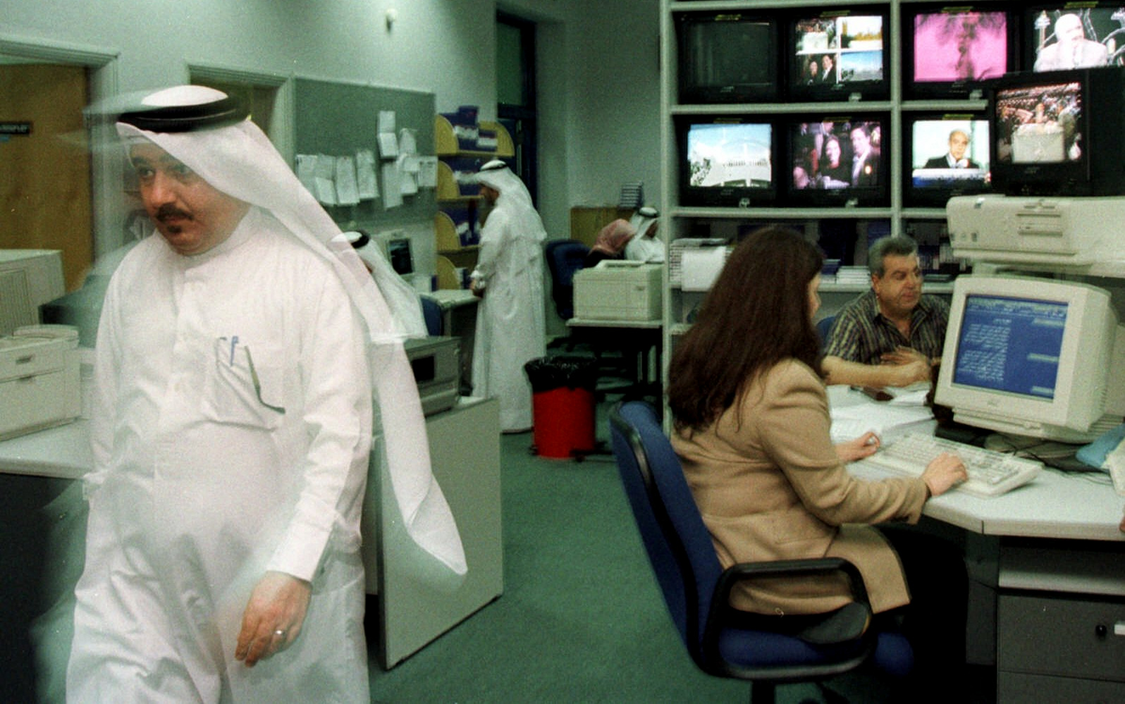 A Qatari man passes colleagues in the studio of Al-Jazeera satellite television channel in Doha, Qatar capital, November 8, 2000. (AP/Kamran Jebreili)