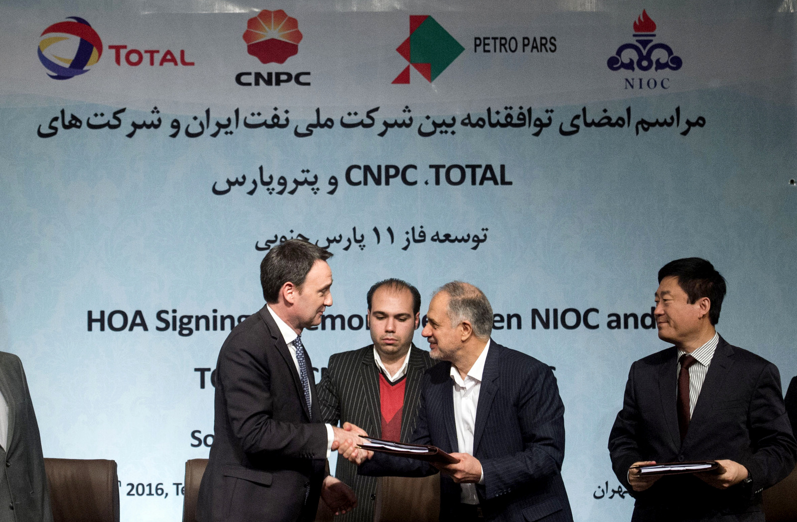 Head of the Middle East and North Africa division at Total, Stephane Michel, left, and managing director of the National Iranian Oil Company Ali Kardor, right, shake hands after signing a $4.8 billion gas agreement in Tehran, Iran, Tuesday, Nov. 8, 2016. (AP/Ebrahim Noroozi)