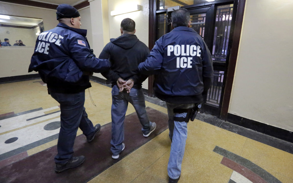 Immigration and Customs Enforcement officers escort an arrestee in an apartment building, in the Bronx borough of New York, during a series of early-morning raids. (AP/Richard Drew, File)