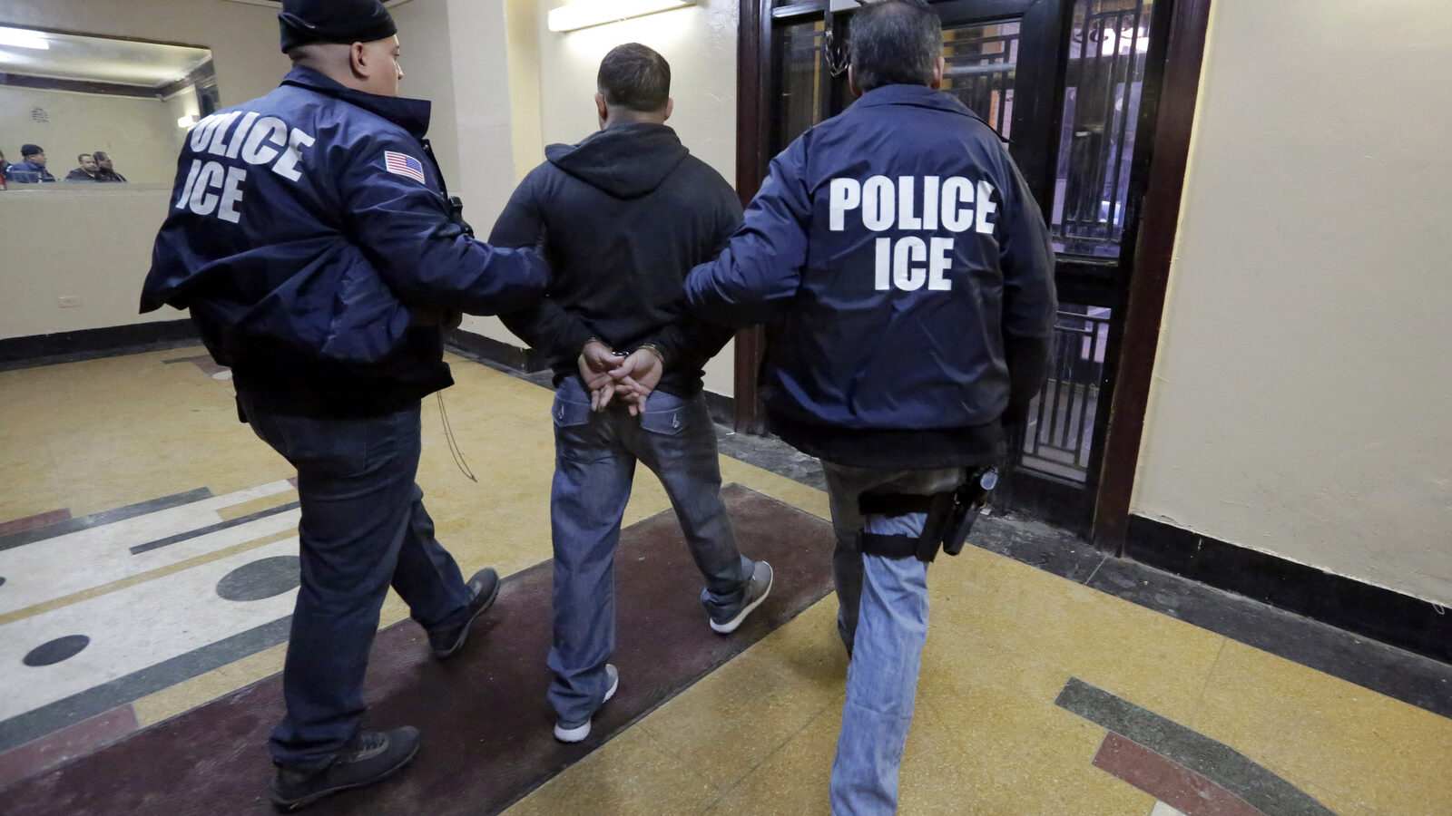 Immigration and Customs Enforcement officers escort an arrestee in an apartment building, in the Bronx borough of New York, during a series of early-morning raids. (AP/Richard Drew, File)
