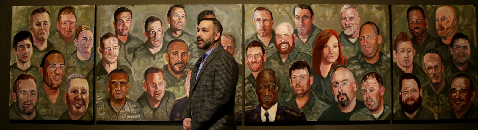 Military veteran Robert Ferrara talks in front of a mural painted by Former President George W Bush during a press preview of an exhibition of Bush's paintings of veterans in Dallas, Tuesday, Feb. 28, 2017.  (AP/LM Otero)