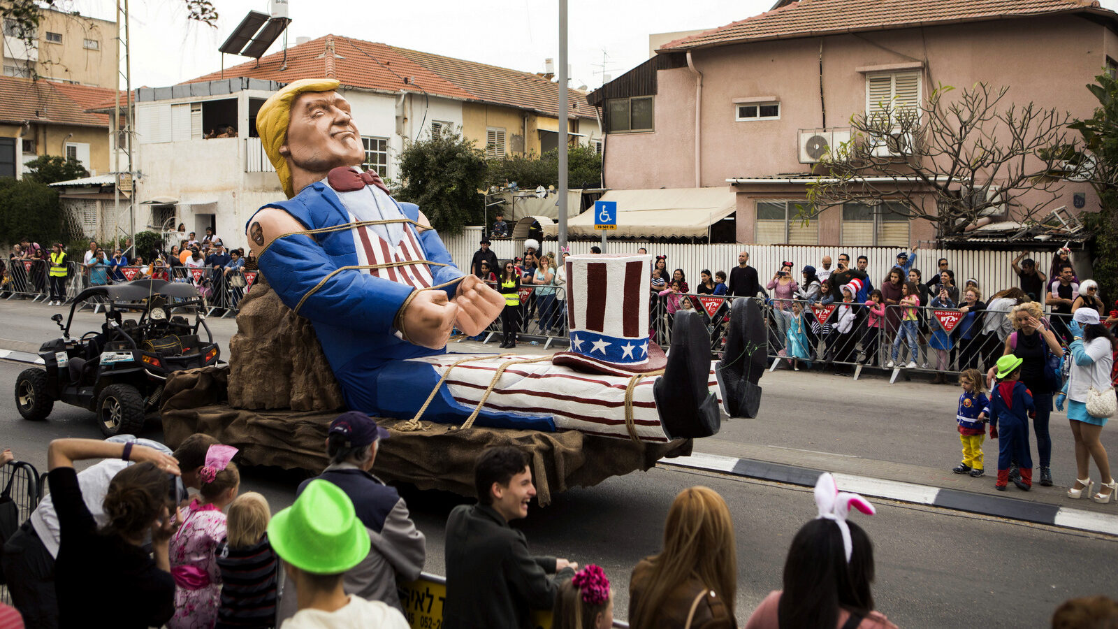 People watch a passing float of U.S. President Donald Trump during a march in a Purim parade in the town of Holon near Tel Aviv, Israel, Sunday, March 12, 2017. The Jewish holiday of Purim celebrates the Jews' salvation from genocide in ancient Persia, as recounted in the Scroll of Esther. (AP/Dan Balilty)