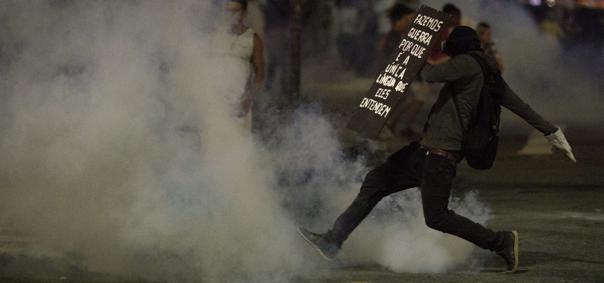 Holding a shield covered with the Portuguese message: "We make war because is the only language they understand," a demonstrator runs amid tear gas during a demonstration against proposed austerity measures in Rio de Janeiro, Brazil, Wednesday, March 15, 2017. People protested across the country against proposed changes to work rules and pensions. (AP/Leo Correa)