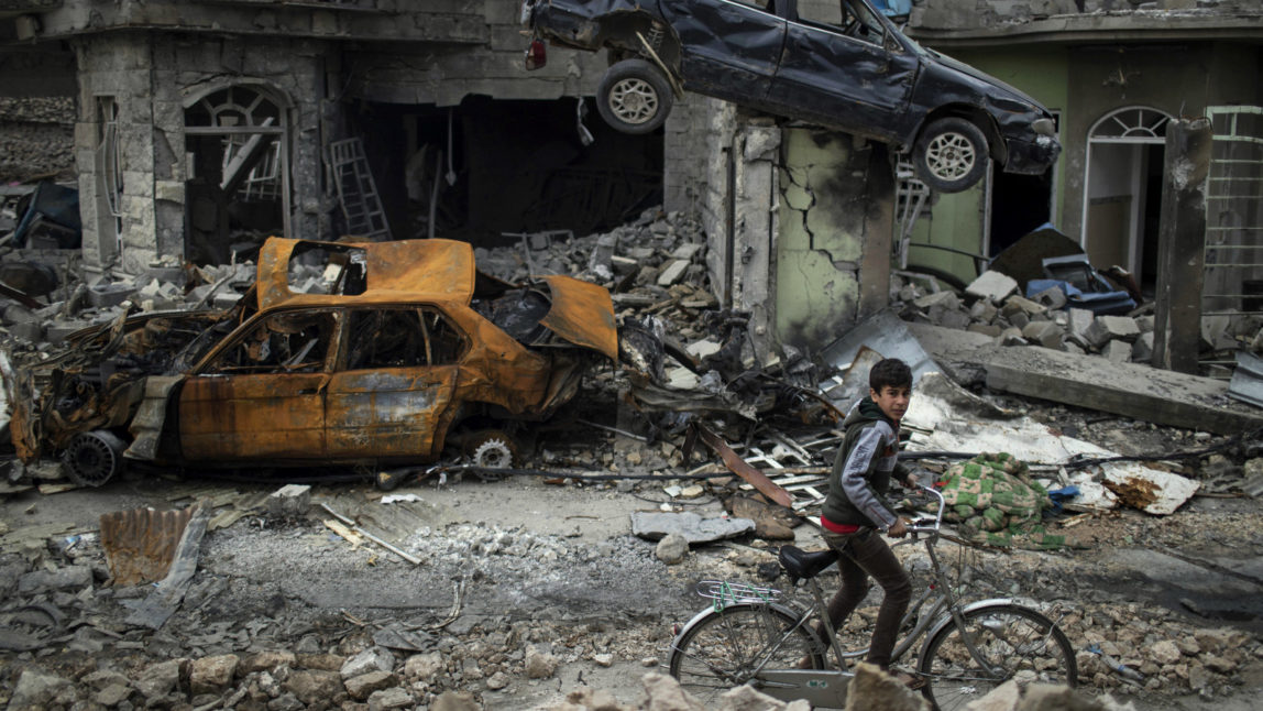A boy rides his bike past destroyed cars and houses in a neighborhood recently liberated by Iraqi security forces, on the western side of Mosul, Iraq, Sunday, March 19, 2017. The battle for western Mosul, including the narrow alleyways of the old city, looks to be the most devastating yet for Iraqi civilians trapped between advancing troops and increasingly desperate ISIS militants. (AP/Felipe Dana)
