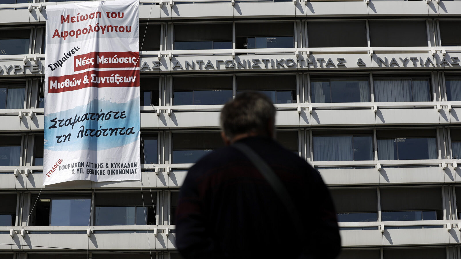 Protesting tax office workers hang a banner from the finance ministry in Athens on Monday, March 20, 2017, that reads: "Reduction of tax free limit means new cuts to salaries and pensions. Stop Austerity." Greece's left-led government is in negotiations with bailout creditors on further budget cuts and reforms required for the release of a new rescue loan installment. (AP/Thanassis Stavrakis)