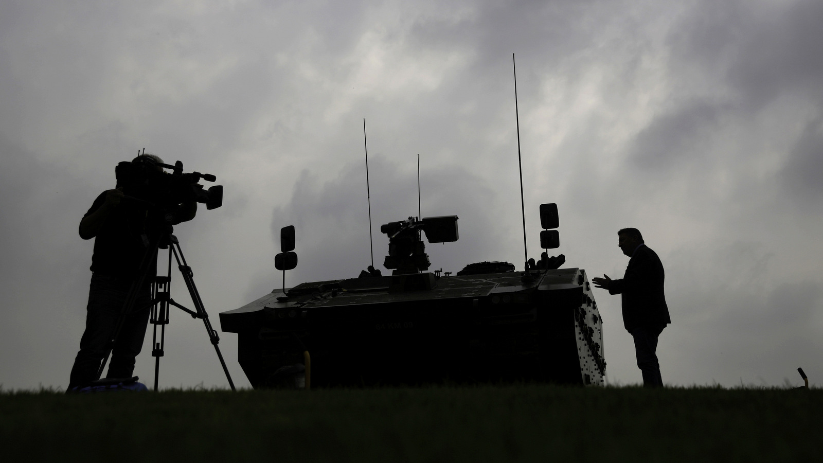 A journalist is silhouetted as he speaks to a cameraman beside a British military armored vehicle at a NATO summit in Newport, Wales. (AP/Matt Dunham)