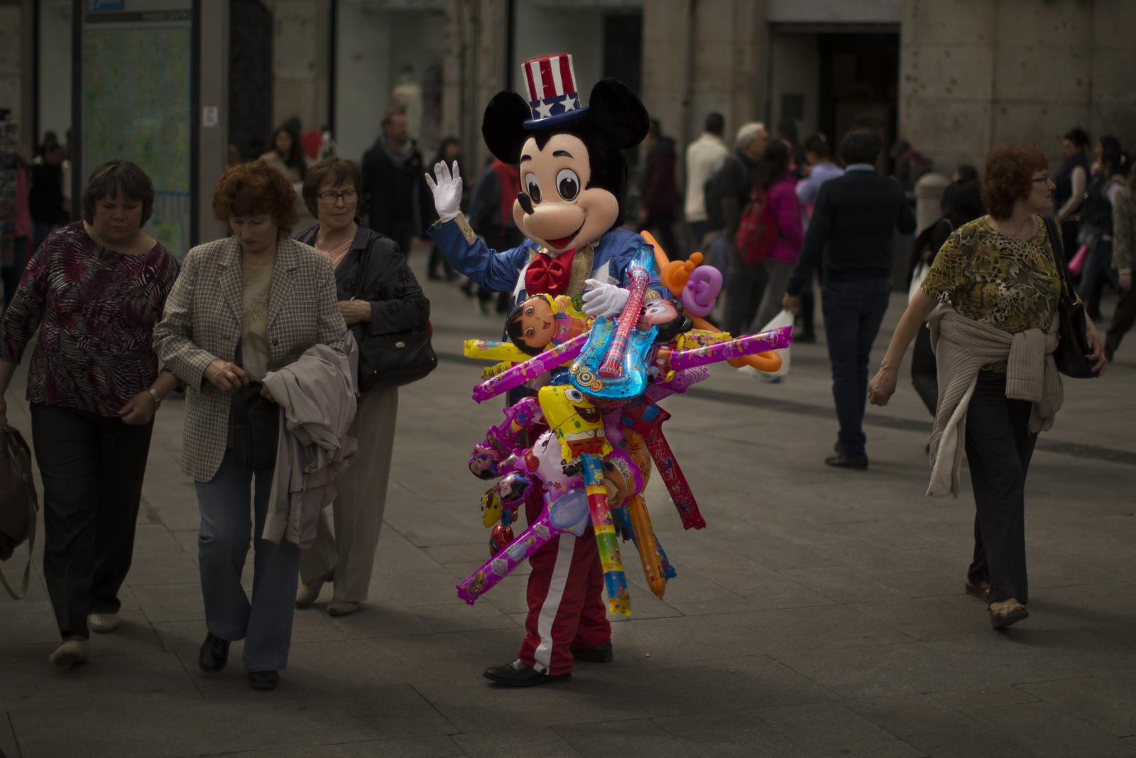 A man sells balloons wearing a Mickey Mouse costume with an US flag on his hat in a tourist area in Madrid, Spain.  (AP/Andres Kudacki)