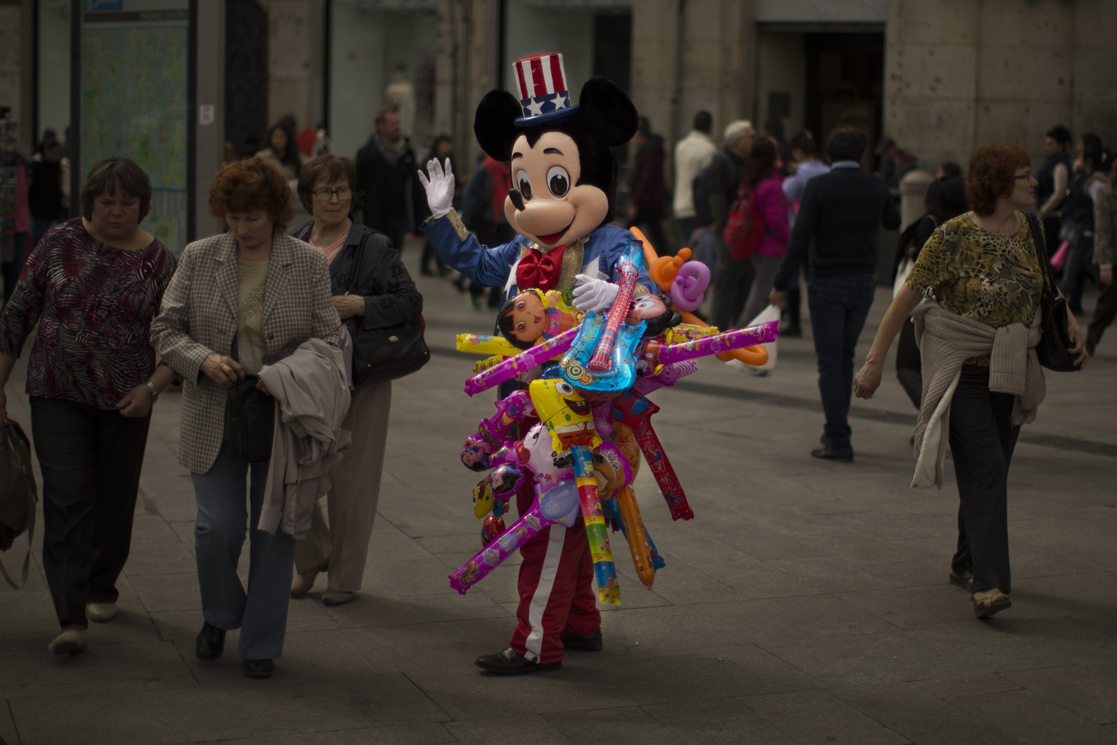 A man sells balloons wearing a Mickey Mouse costume with an US flag on his hat in a tourist area in Madrid, Spain. (AP/Andres Kudacki)