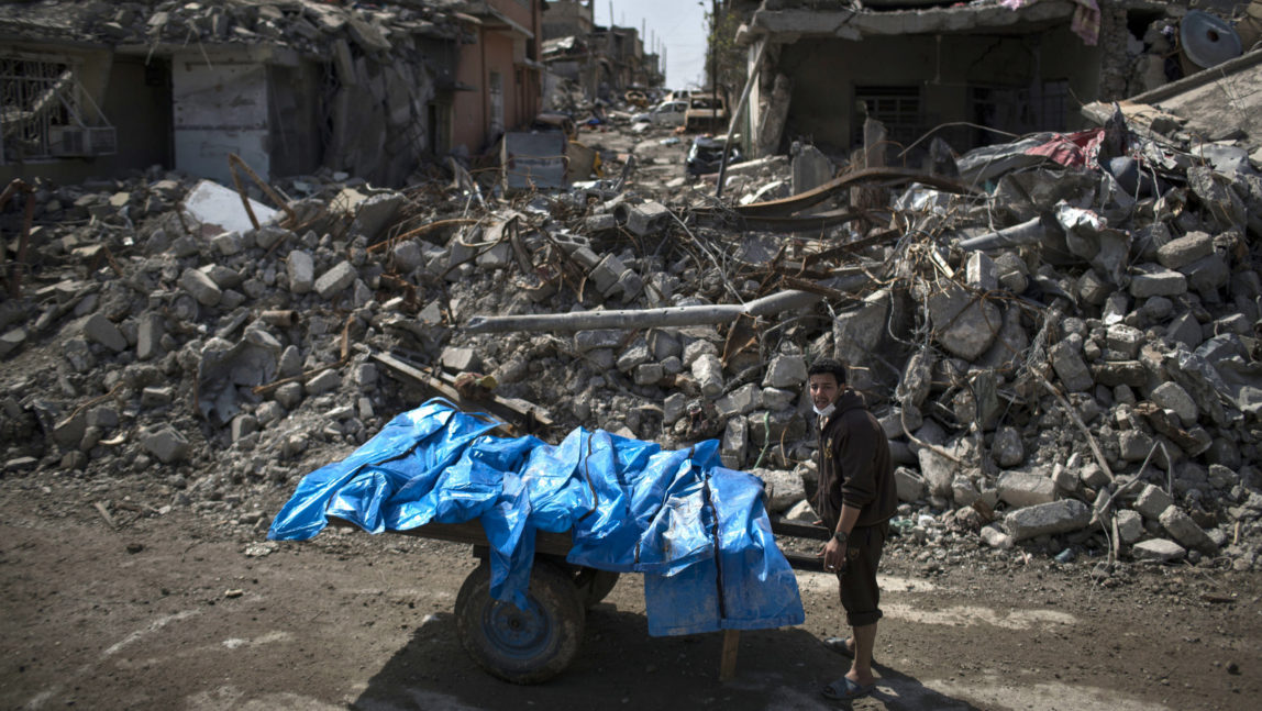 A resident carries the bodies of six people killed during fights between Iraq security forces and Islamic State on the western side of Mosul, Iraq, Friday, March 24, 2017. Residents of the Iraqi city's neighborhood known as Mosul Jidideh at the scene say that scores of residents are believed to have been killed by airstrikes that hit a cluster of homes in the area earlier this month (AP Photo/Felipe Dana)