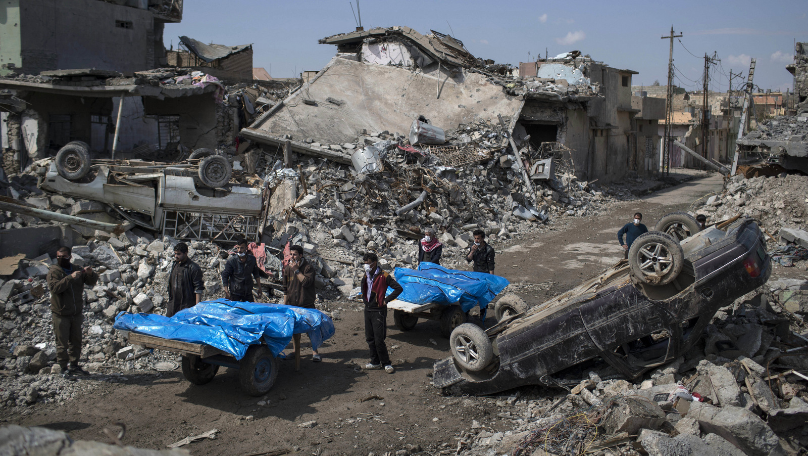 Residents carry the body of several people killed during fights between Iraq security forces and Islamic State on the western side of Mosul, Iraq, Friday, March 24, 2017. Residents of the Iraqi city's neighborhood known as Mosul Jidideh at the scene say that scores of residents are believed to have been killed by airstrikes that hit a cluster of homes in the area earlier this month (AP Photo/Felipe Dana)