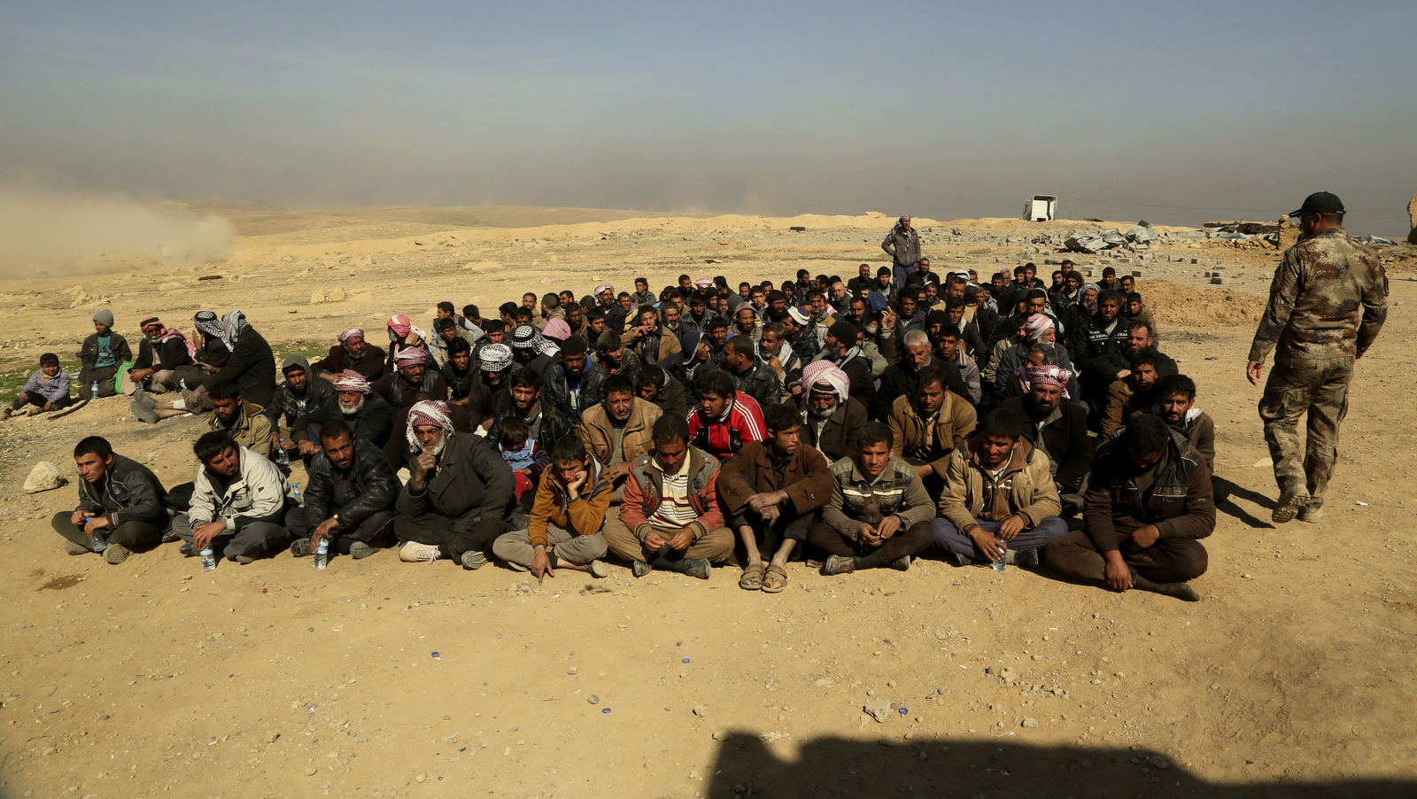 Displaced men who fled their homes due to fighting between Iraqi security forces and ISIS militants wait for a security check at an Army base, west of Mosul, Iraq, Feb. 26. 2017. (AP/Khalid Mohammed)