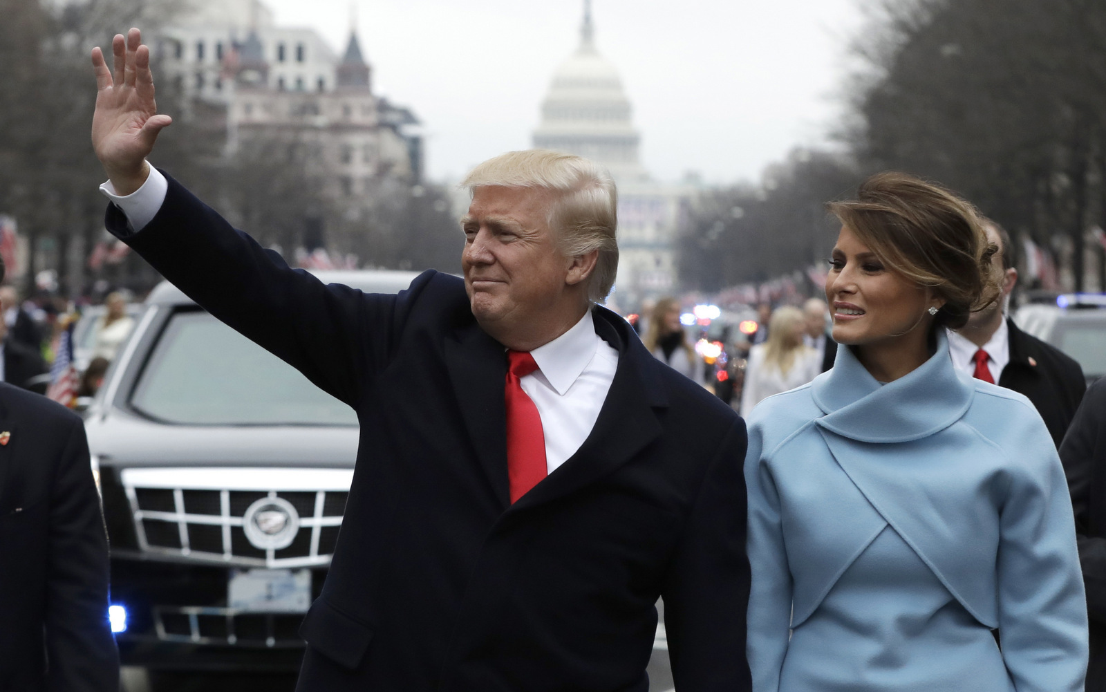 Donald Trump waves as he walks with first lady Melania Trump during the inauguration parade on Pennsylvania Avenue in Washington. Trump raised $107 million for his inaugural festivities.  (AP/Evan Vucci)