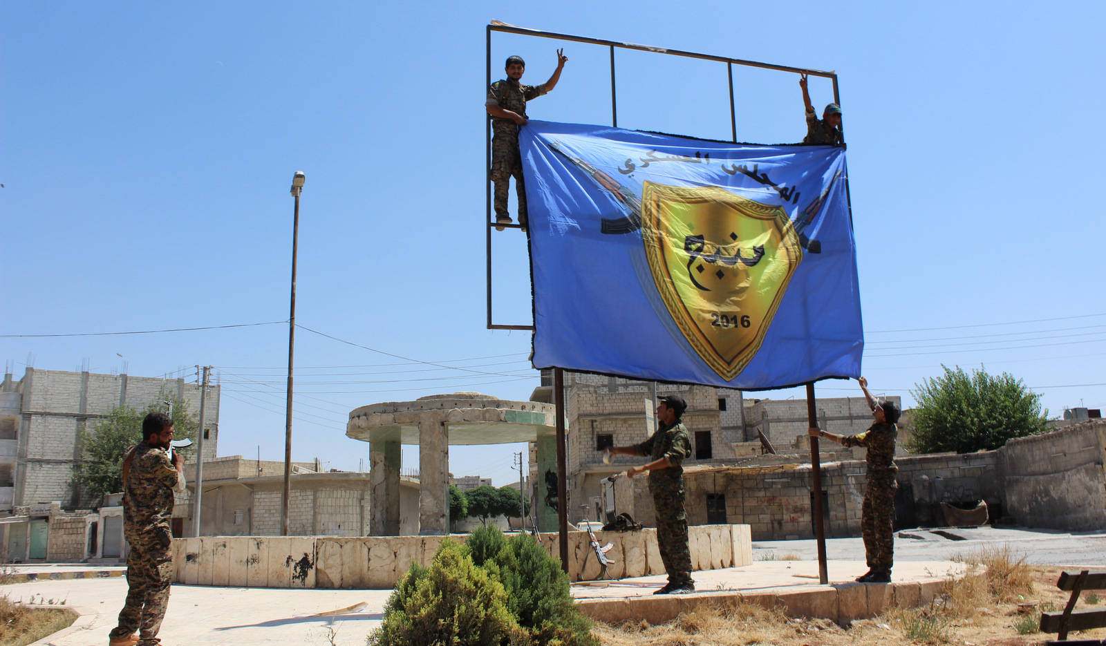 Les Forces démocratiques syriennes, soutenues par les États-Unis et dirigées par les Kurdes, lèvent leur drapeau au centre de la ville de Manbij après avoir chassé l'Etat islamique de la zone, dans la province d'Alep, en Syrie. (ANHA via AP)