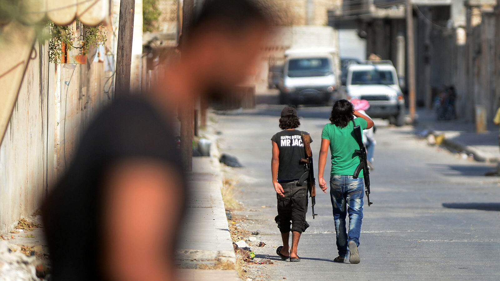 An unidentified man walks past young Free Syrian Army fighters patrolling the streets of Jarablus, Syria, Aug. 31, 2016. (Ismail Coskun/IHA/AP)