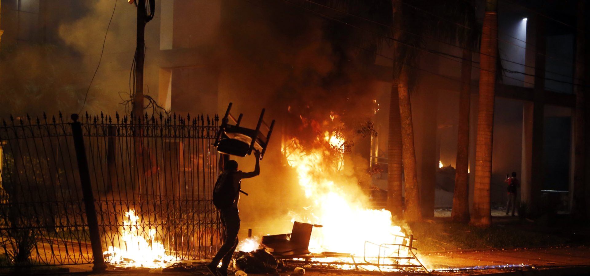 A protester carries a chair to a fire outside the congress building during clashes between police and protesters opposing an approved proposed constitutional amendment that would allow the election of a president to a second term, in Asuncion, Paraguay, Friday, March 31, 2017. (AP/Jorge Saenz)
