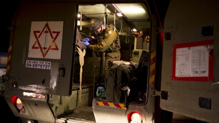 In this Thursday, April 6, 2017 photo made in Israeli controlled Golan Heights, Israeli military medics assist wounded Syrians. Seven wounded Syrians crossed into Israeli controlled Heights Thursday night have received immediate treatment and were hospitalized later on. They are the latest group of Syrian fighters receiving free medical care through an Israeli military program operating since 2013. (AP/Dusan Vranic)
