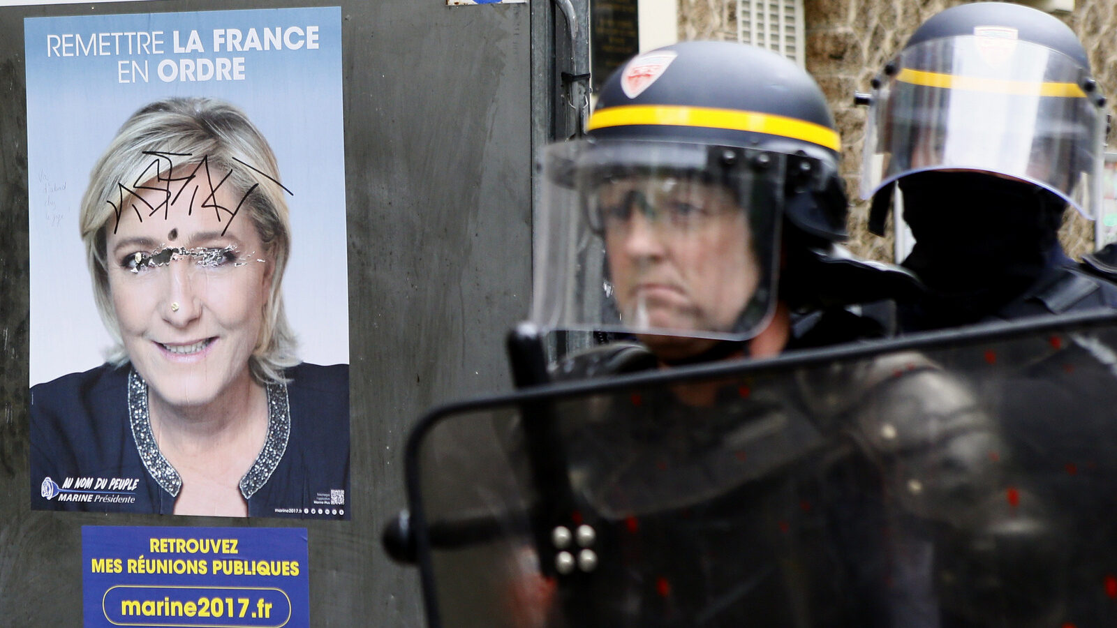 French anti-riot officers stand next to a placard of far-right National Front leader and presidential candidate Marine Le Pen during a protest march from suburban Aubervilliers to Paris, Sunday, April 16, 2017. Le Pen is one of the top contenders in France first-round presidential vote on April 23. A presidential runoff is being held May 7. (AP/Francois Mori)
