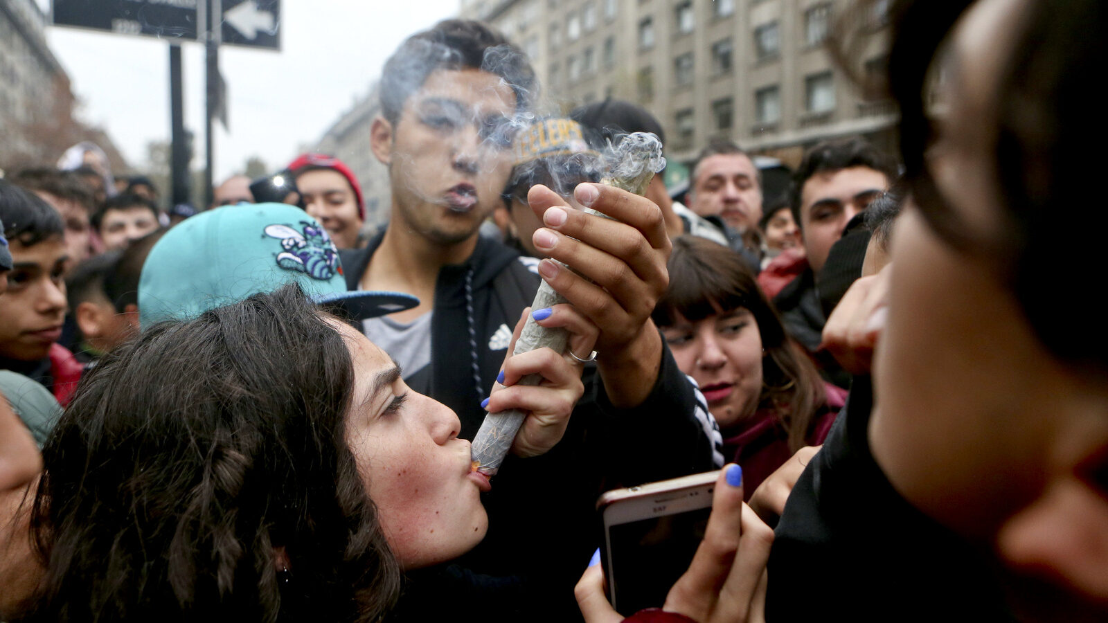 A youth smokes a joint during a demonstration in favor of the legalization of marijuana near La Moneda presidential palace in Santiago, Chile, Thursday, April 20, 2017. In Chile, it's only legal to buy and sell marijuana seeds for collection, and to use the herb for medicinal purposes when approved by the government. (AP/Esteban Felix)