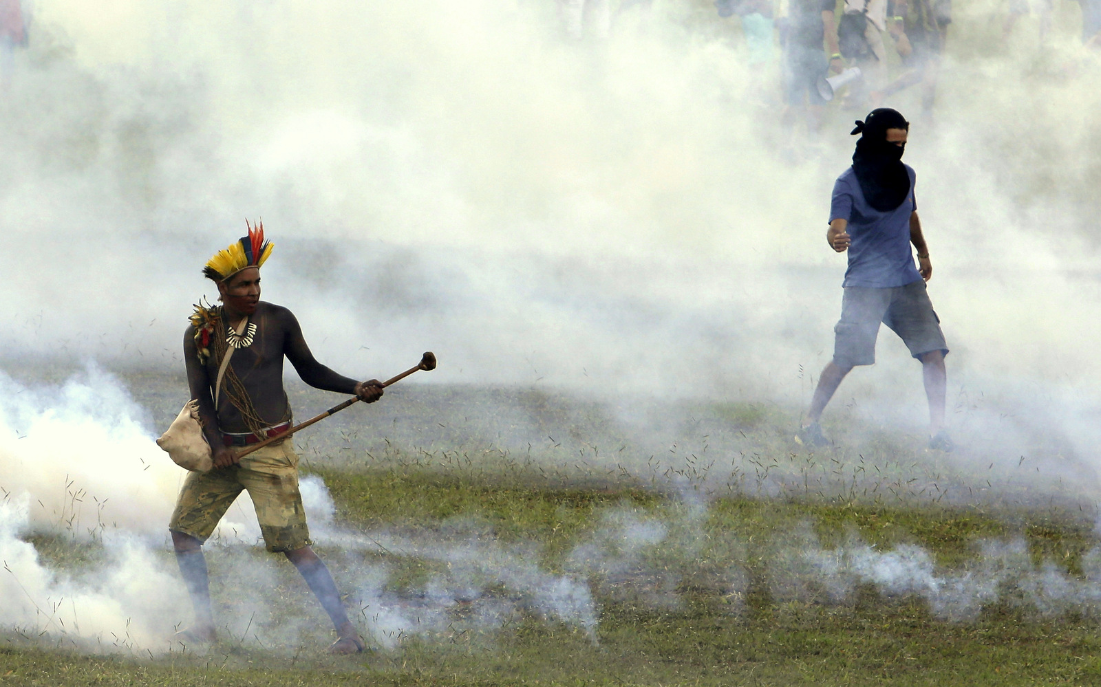 An indigenous man, left, stands amid tear gas fired by police outside the National Congress during a demonstration for the demarcation of indigenous lands in Brasilia, Brazil, Tuesday, April 25, 2017. Indigenous leaders say the government of President Michel Temer is working to roll back protections in various parts of the Amazon and allowing ranchers and other big-money interest to steal their lands. (AP/Eraldo Peres)