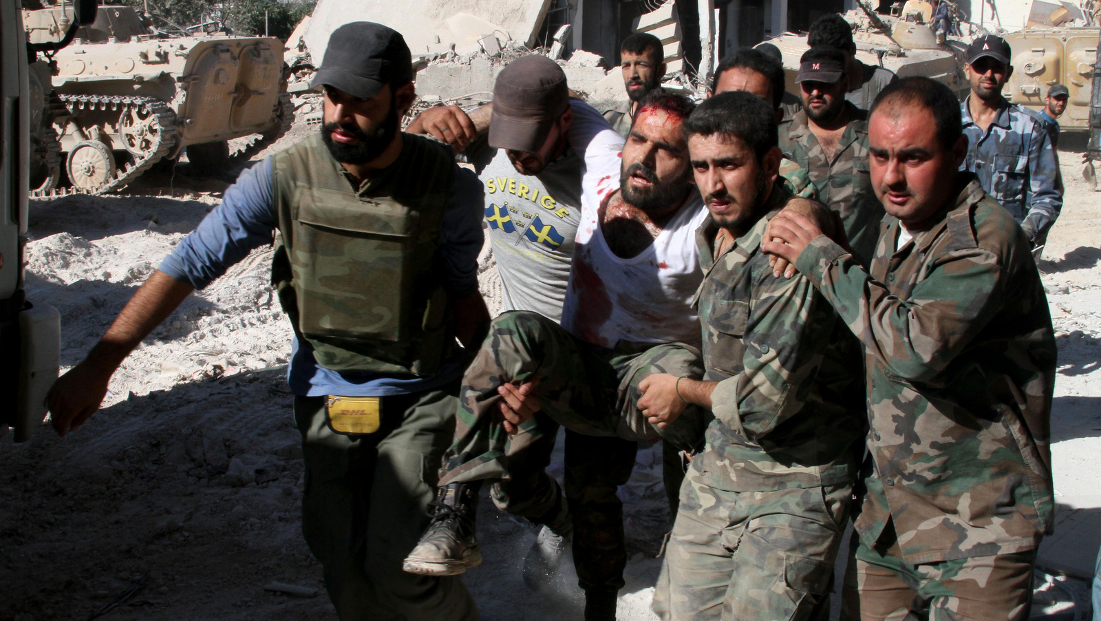 Syrian army soldiers evacuate a comrade injured during heavy clashes with Syrian rebels in the Jobar neighborhood of Damascus, Syria, Saturday, Aug. 24, 2013. (AP Photo)