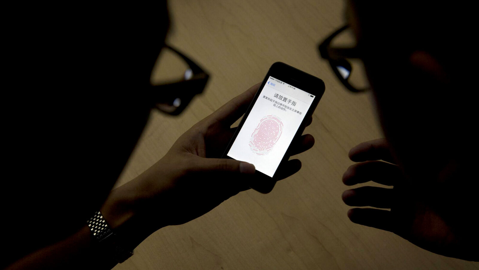 An Apple employee instructs a journalist on the use of the fingerprint scanner technology built into the company's iPhone 5S during a media event in Beijing. Watchdog groups are concerned that U.S. Customs and Border Protection agents are searching the phones and other digital devices of international travelers at border checkpoints in U.S. airports. (AP/Ng Han Guan)