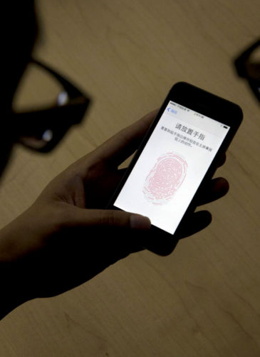 An Apple employee instructs a journalist on the use of the fingerprint scanner technology built into the company's iPhone 5S during a media event in Beijing. Watchdog groups are concerned that U.S. Customs and Border Protection agents are searching the phones and other digital devices of international travelers at border checkpoints in U.S. airports. (AP/Ng Han Guan)