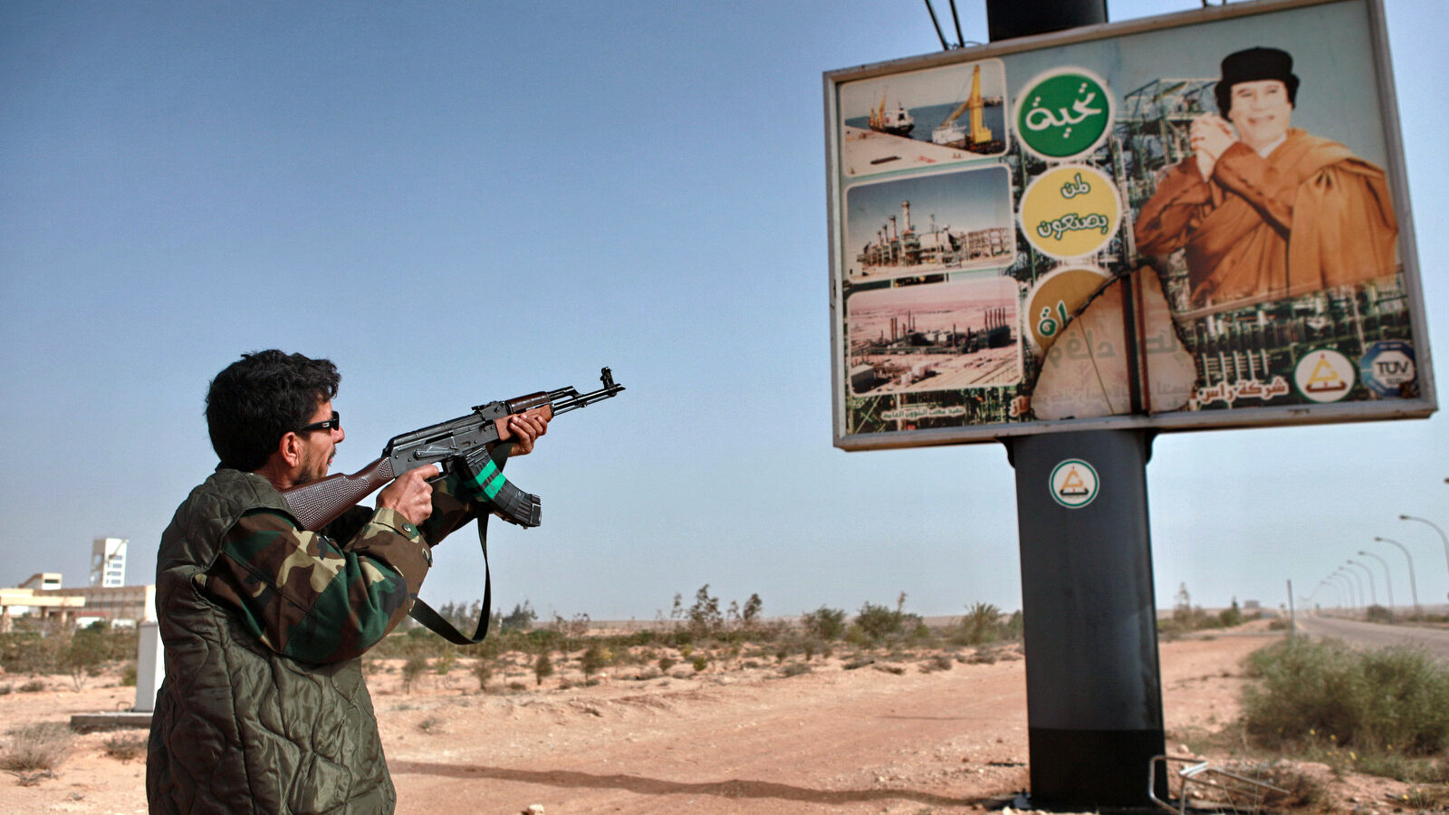 An armed Libyan rebel shoots an AK-47 at a poster of Muhammar Gaddafi in the captured rebel town of Ras-Lanuf in the east of the country (Photo: Andrey Stenin/Sputnik)