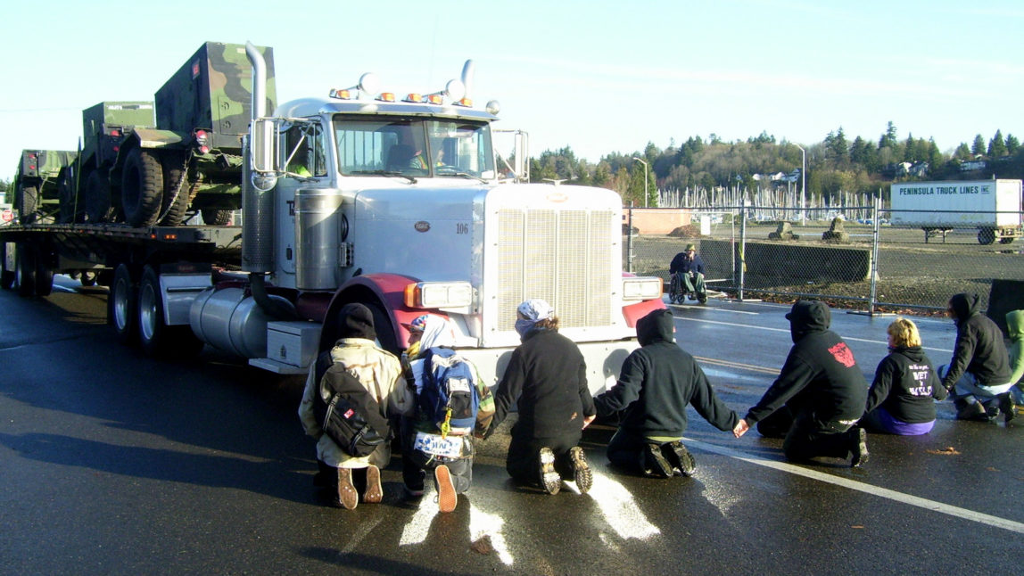 Activists sit down in front of a truck carrying military equipment thus taking control of the Port of Olympia entrance for the second time in 5 days. (Photo: Phoebe Blanding/olywip.org)