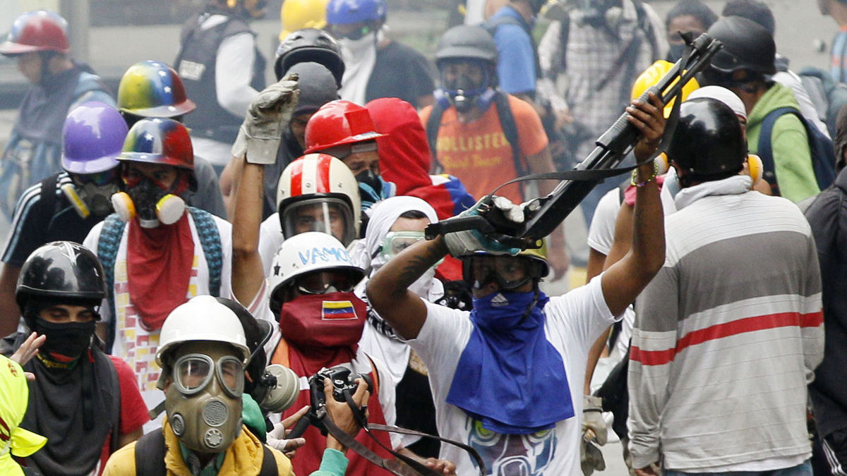 An anti-government protester wields a shotgun taken from security forces during clashes in Caracas, Venezuela, May 8, 2017. The protest movement has drawn masses of people into the streets nearly every day since March, has left some three dozen dead. (AP/Ariana Cubillos)