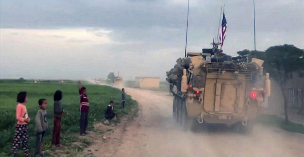 Syrian children watch as U.S. forces patrol a rural road in the village of Darbasiyah, in northern Syria. U.S. armored vehicles are deploying in areas in northern Syria along the tense border with Turkey, a few days after a Turkish airstrike that killed 20 U.S.-backed Kurdish rebels, April 28, 2017. (AP/APTV)