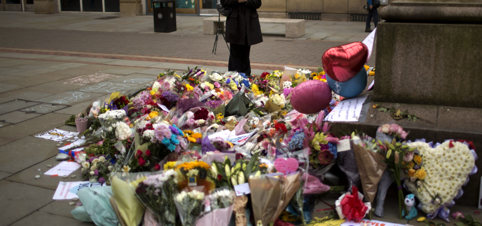 A woman stands next to flowers offered for the victims of a suicide attack at a concert by Ariana Grande that killed more than 20 people Monday night in central Manchester, Britain, May 24 2017. (AP/Emilio Morenatti)