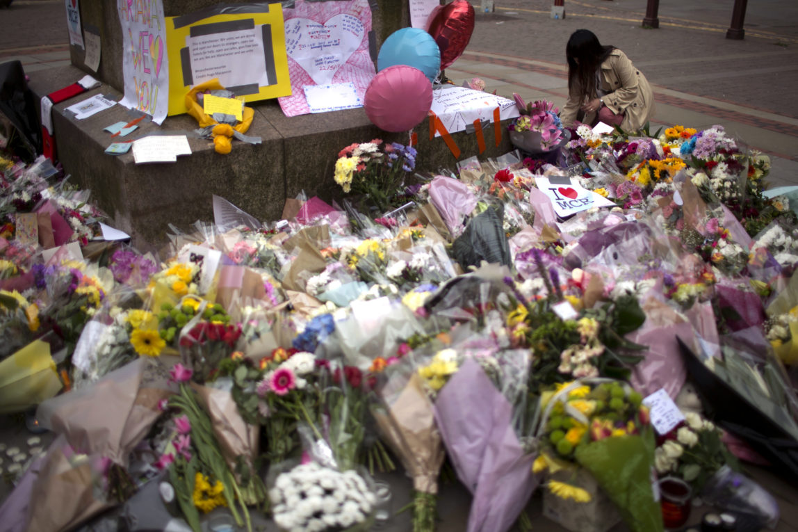 A woman places flowers at a memorial for the victims of a suicide attack at a concert by Ariana Grande that killed more than 20 people Monday night in central Manchester, Britain, Wednesday, May 24, 2017. (AP/Emilio Morenatti)