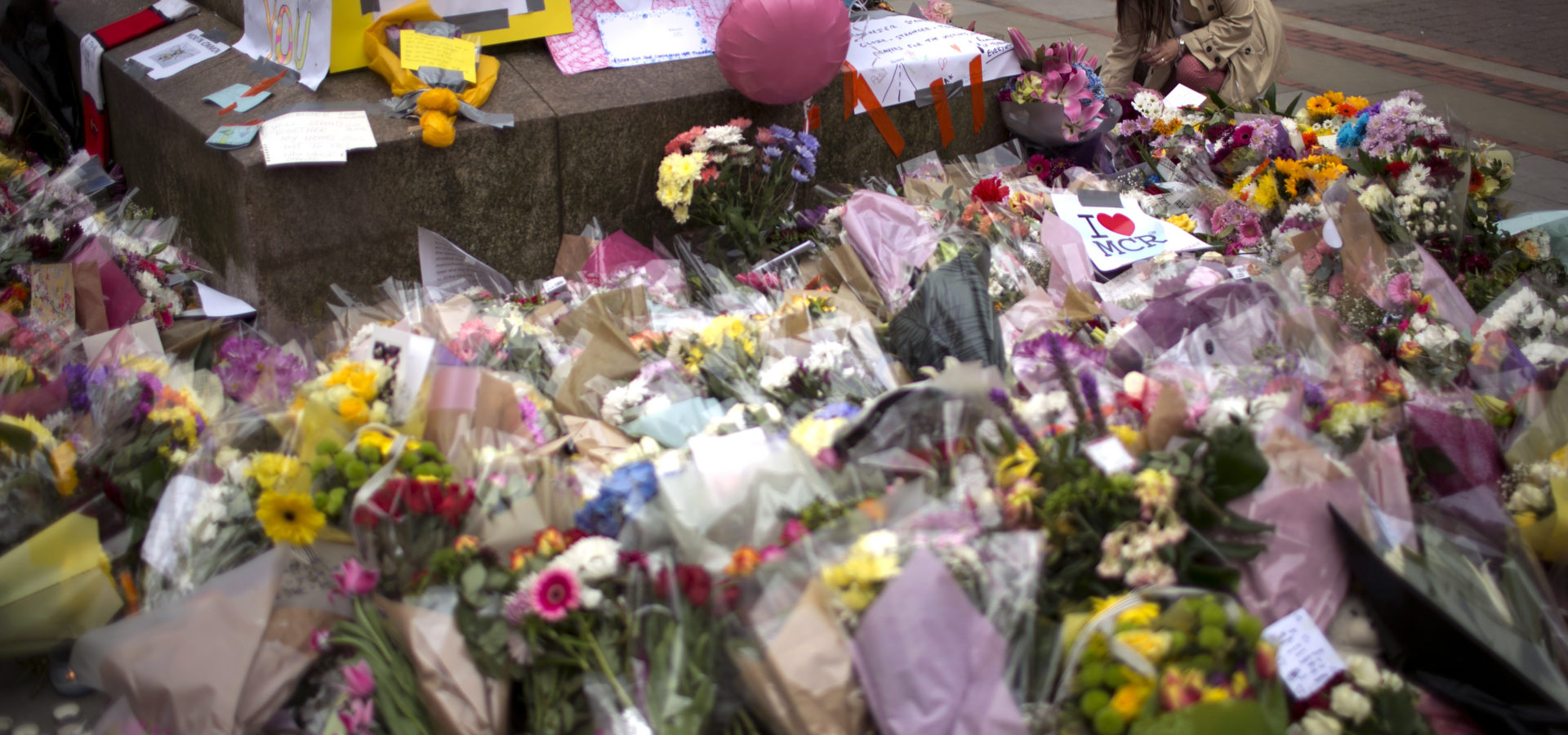 A woman places flowers at a memorial for the victims of a suicide attack at a concert by Ariana Grande that killed more than 20 people Monday night in central Manchester, Britain, Wednesday, May 24, 2017. (AP/Emilio Morenatti)