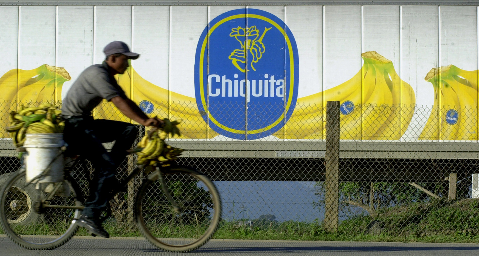 A man on a bicycle rides by a banana trailer in La Lima, Honduras Thursday Nov. 29, 2001. (AP/Esteban Felix)