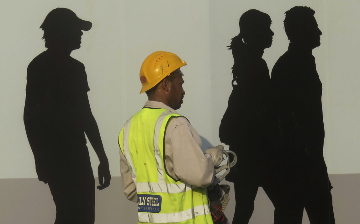 A worker passes by a wall painting in Dubai, United Arab Emirates. (AP/Kamran Jebreili)